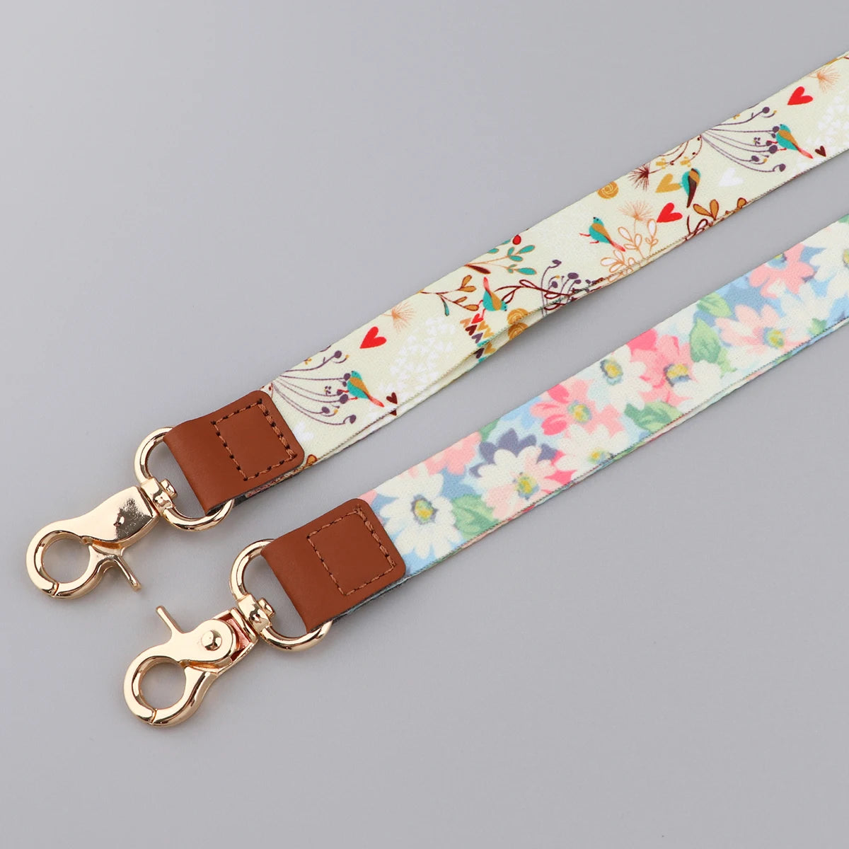 A beige floral patterned leather lanyard strap with a brass clasp and brown leather attachment.