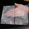 A hand is holding a sheet of transparent bubble wrap padded shipping bags.