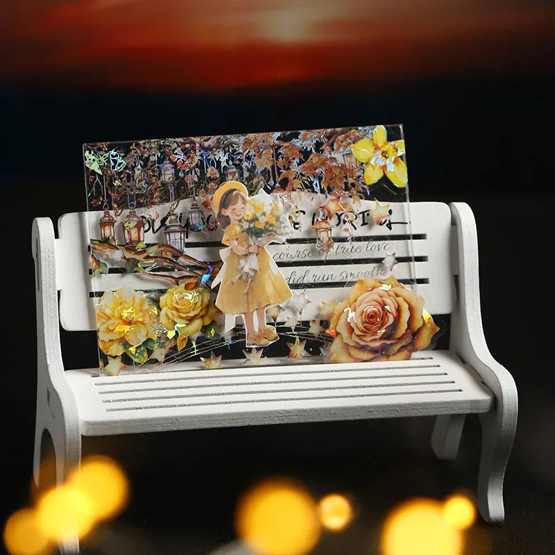 A decorative roll of PET washi tape featuring floral and nature elements displayed on a white wooden bench.