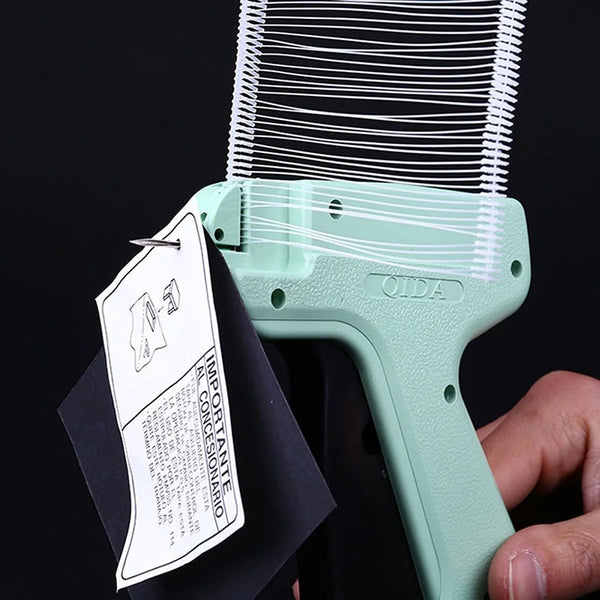 A hand holds a light green professional apparel tagging gun kit with a black tag.