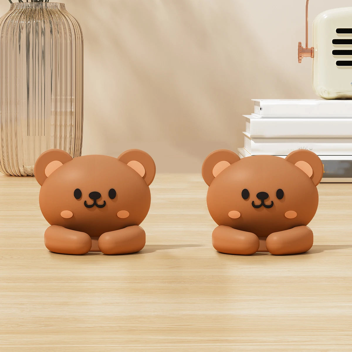 Two round, brown cartoon bear desk cable organizers sitting on a light wooden surface.