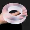 A hand holds a roll of clear, translucent adhesive tape with fine, parallel lines on a dark background.
