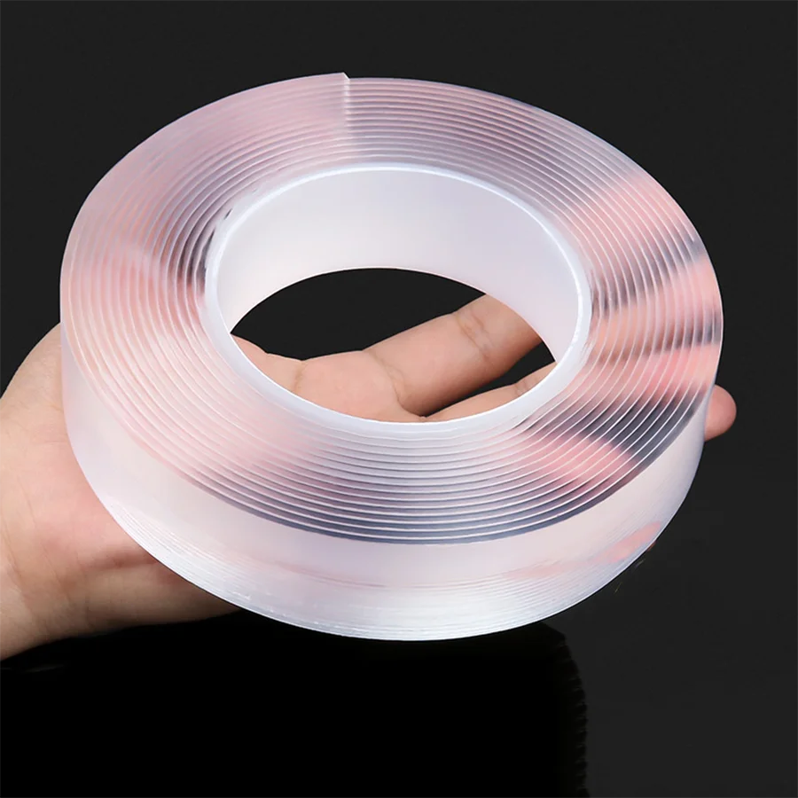 A hand holds a roll of clear, translucent adhesive tape with fine, parallel lines on a dark background.