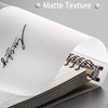 Gros plan d'un carnet à texture mate blanc avec une signature manuscrite sur la page.