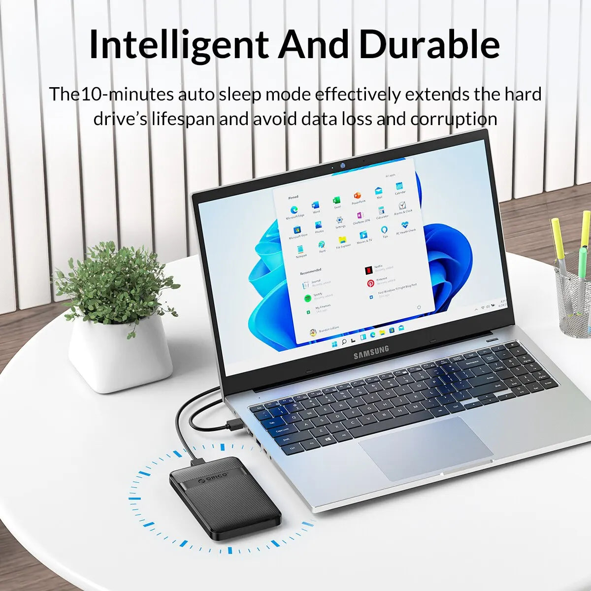 A silver laptop is shown with a hard drive enclosure connected, demonstrating an intelligent and durable feature.