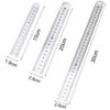 A set of precision stainless steel measuring rulers showing various centimeter and inch markings.