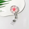 A clear retractable ID badge holder featuring a pink floral pull buckle on a white background.