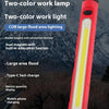 A red and black LED handheld work light with a yellow light, shown outdoors.
