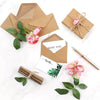Eine Sammlung von Kraftpapier-Umschlägen mit Schnur, rosa Rosen und grünen Blättern.