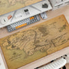 A large, detailed map of Middle-earth is displayed on a wooden desk next to a gaming mouse pad and other desk accessories.