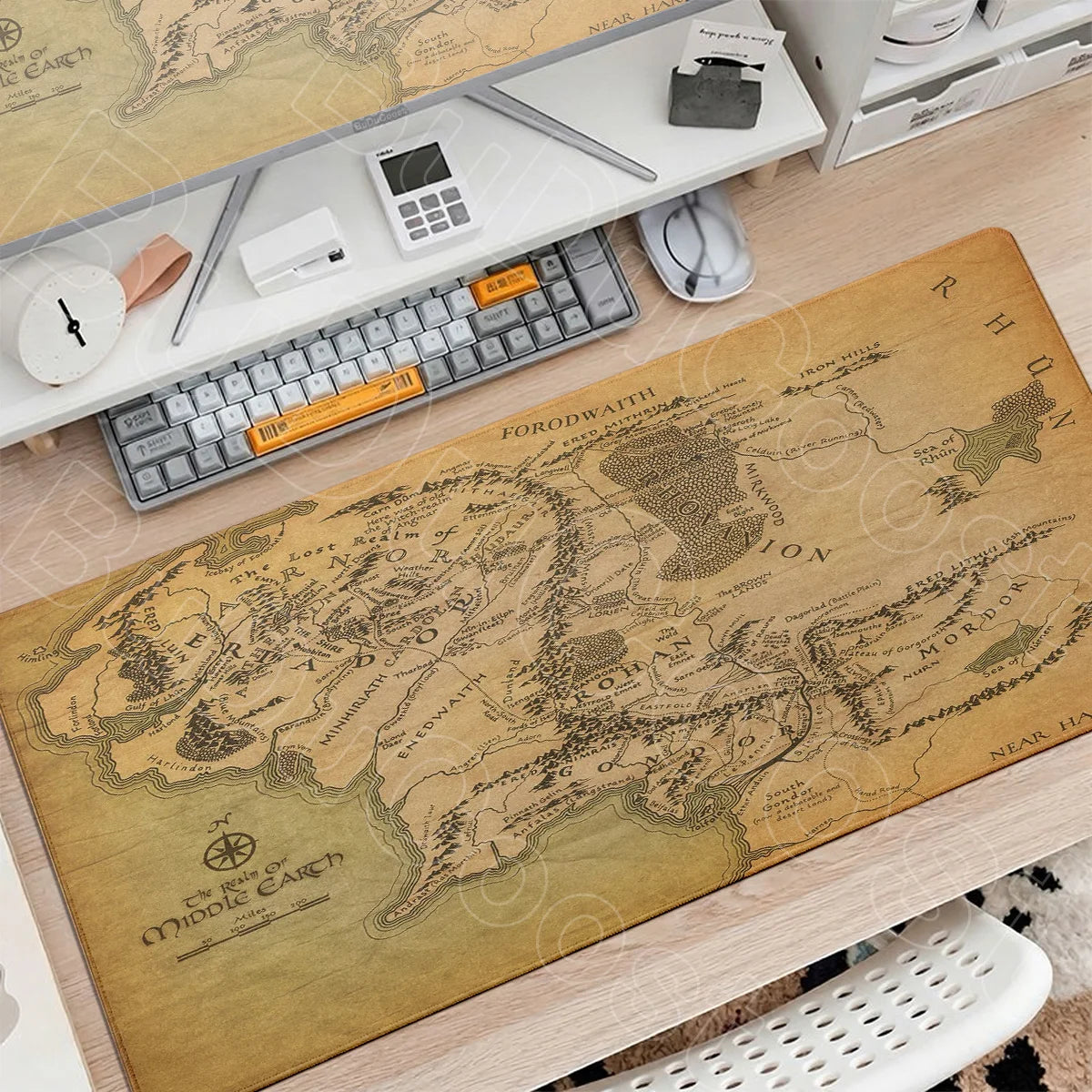 A large, detailed map of Middle-earth is displayed on a wooden desk next to a gaming mouse pad and other desk accessories.