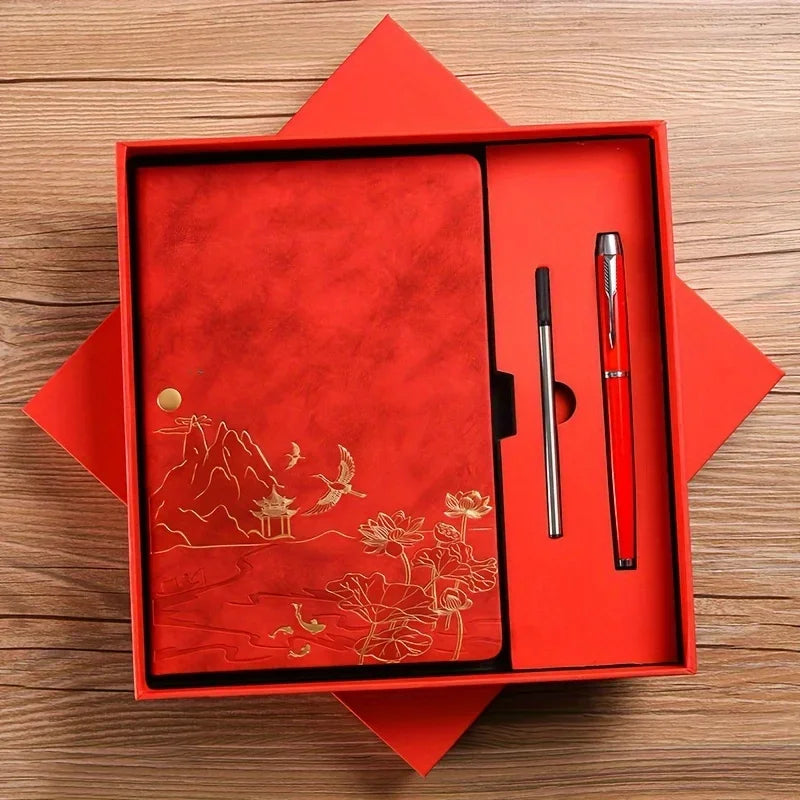 A red luxury PU leather notebook set with a gold embossed landscape design and a silver pen inside a square box.