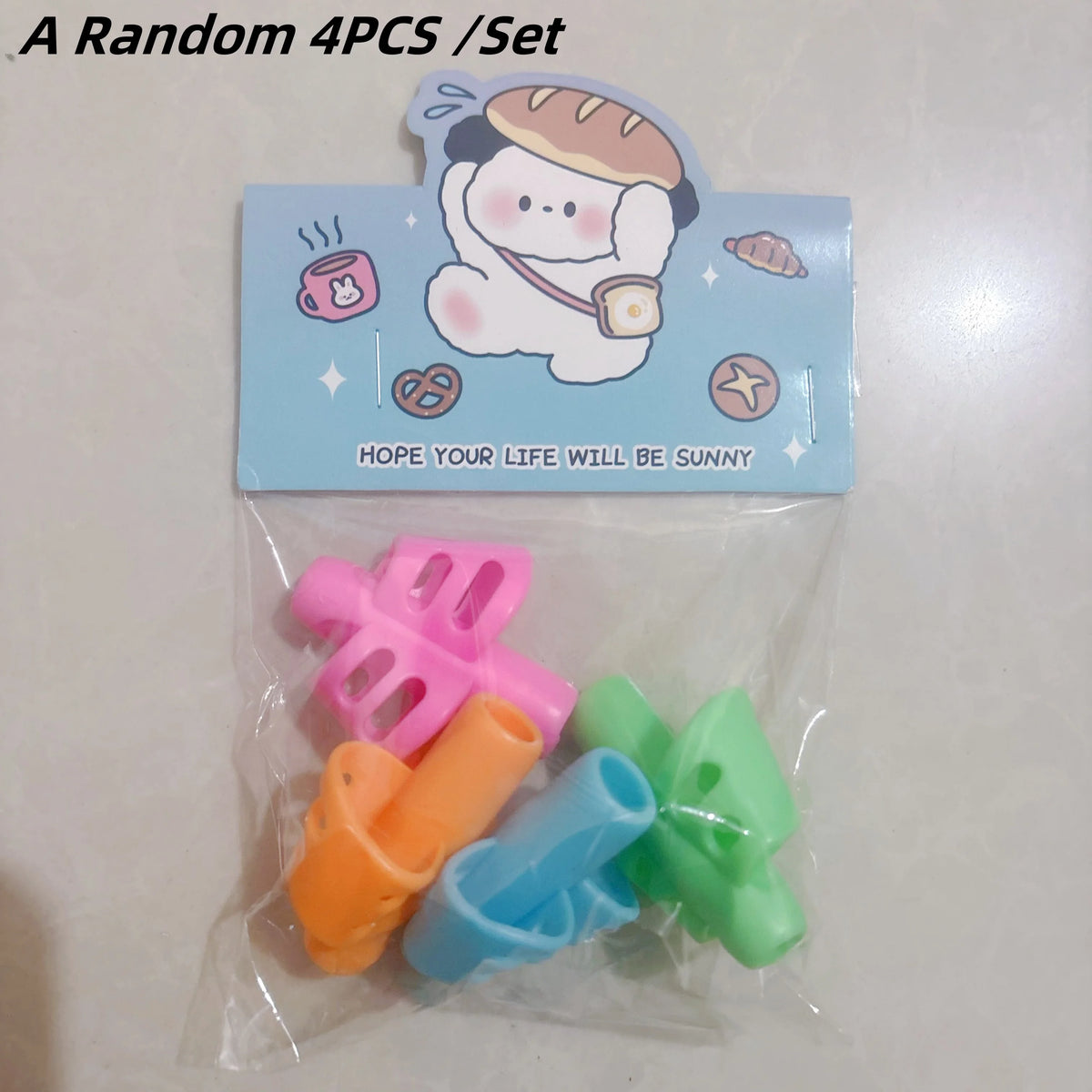 A set of four colorful silicone pencil grips for kids with a cartoon design.
