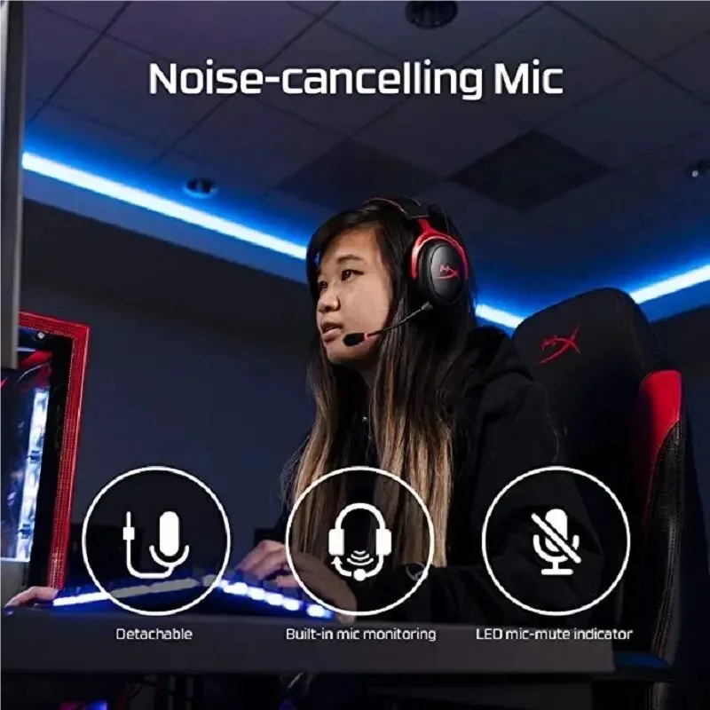 A woman wearing a black hoodie and headphones is using a computer setup with a noise-cancelling microphone.