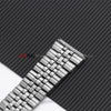 A close-up view of a polished stainless steel watch band with a folding clasp resting on a black textured surface.