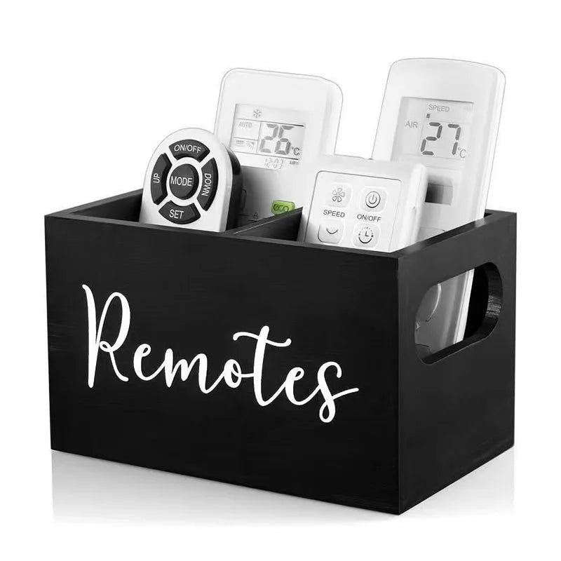 A black wooden storage box with dividers holding several white remote controls and small electronic devices.