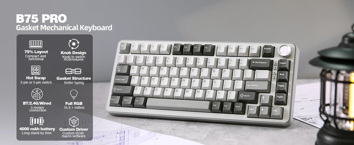 A white B75 PRO gasket mechanical keyboard is shown on a desk next to some blueprints.