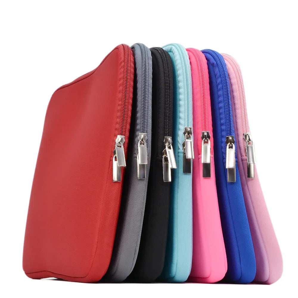 Una fila de fundas para laptop de algodón delgadas y coloridas en tonos rojo, gris, negro, verde azulado, rosa y azul.
