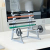 A silver barbell rack desk organizer holding various colored bars and a pen holder.