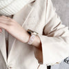 A close-up of a wrist wearing a resin beaded watch band with a three-bead design on a light blazer sleeve.