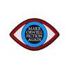 A lapel pin featuring an oval design with concentric circles in black, white, and blue, displaying the text MAKE ORWELL FICTI