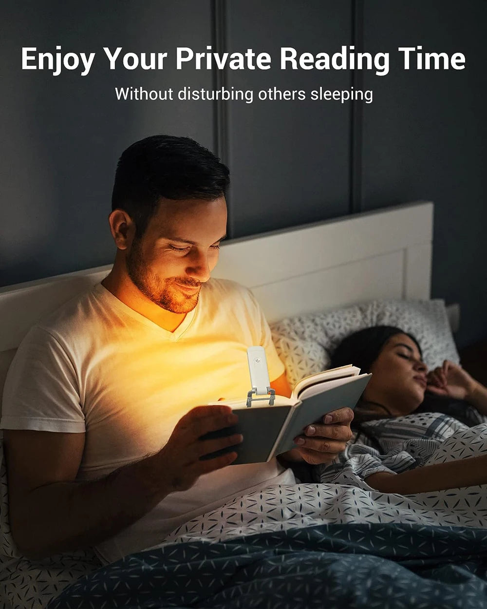 A man is reading a book in bed with a USB rechargeable LED book reading light.