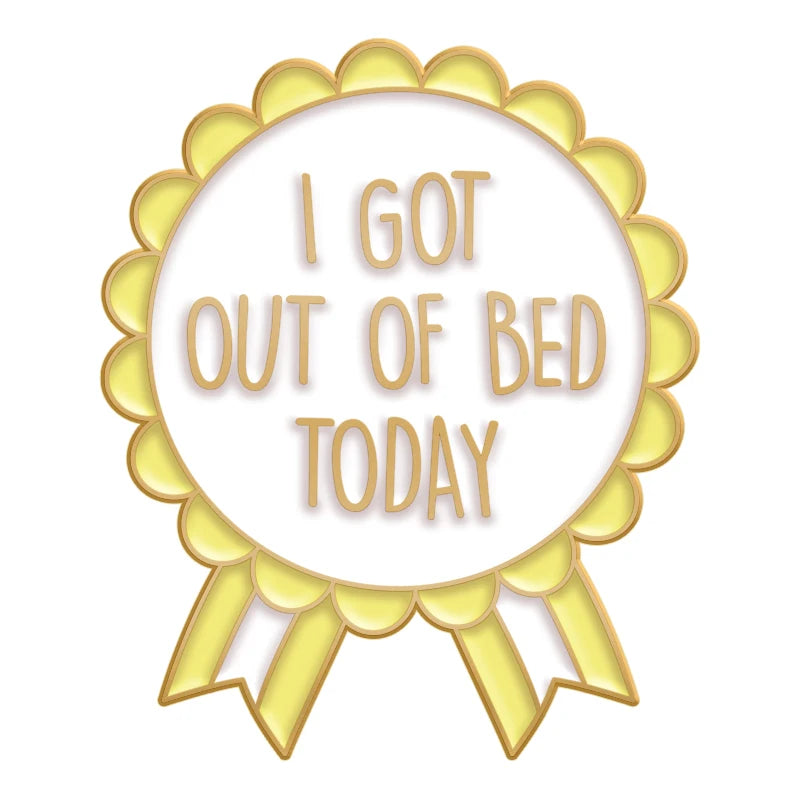 A gold-edged circular pin featuring the text I GOT OUT OF BED TODAY