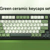 A set of bright green ceramic keycaps for a mechanical keyboard displayed on a green desk.
