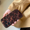 A hand holds an Amber retro shockproof phone case for iPhone against a light brown background.