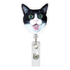 A black and white cat face charm attached to a retractable ID badge holder with a crocodile clip.