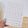 A sheet of metallic 3D heart and star nail art stickers for decorative use.