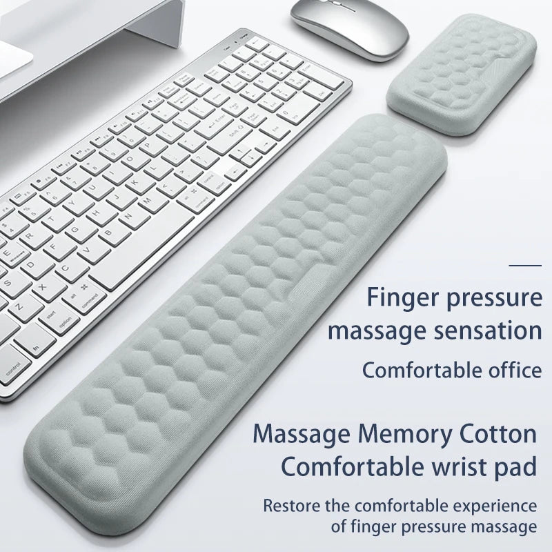 A gray ergonomic keyboard and mouse with a silicone massage wrist pad shown on a white surface.