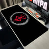 A black gaming mouse pad featuring a red Berserk anime logo on a wooden desk.