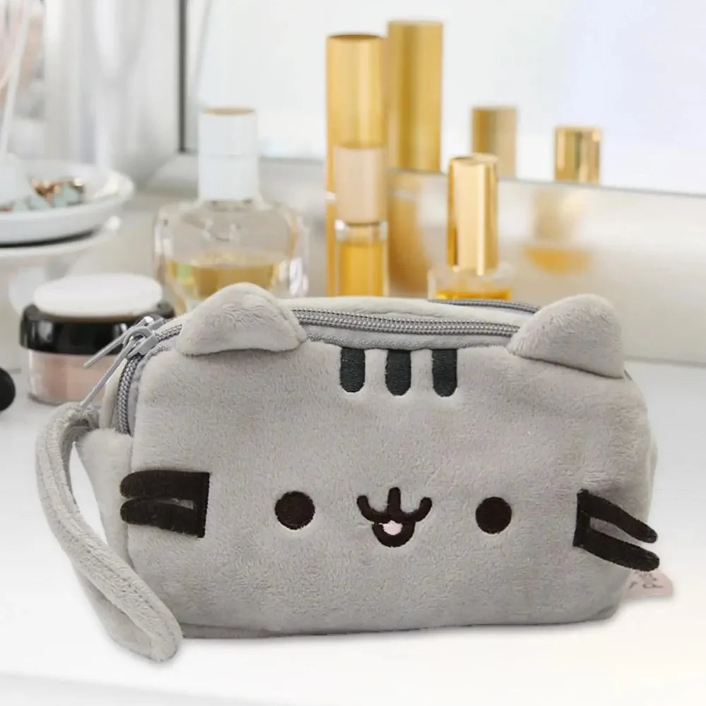 A gray plush cat pencil case with black accents and a zipper, resting on a white surface.