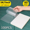 A hand holds a clear thermal laminating pouch, showing its size and material on a grid background.