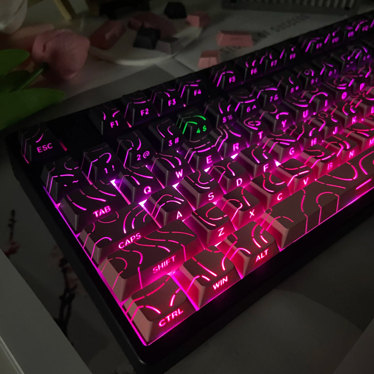 Primer plano de un teclado mecánico con teclas de gradiente rosa y púrpura vibrantes iluminadas.