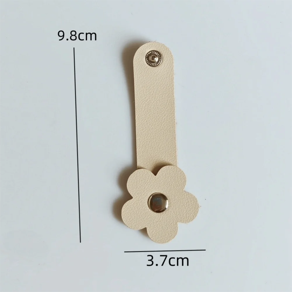 A beige leather flower cable organizer with a loop and a flower shape, measuring 9.8cm by 3.7cm.