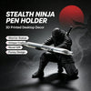 A matte black ninja figurine holding a pen, used as a 3D printed desktop decor pen holder.