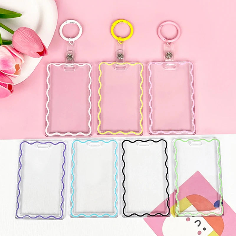 A set of clear acrylic card holders with colorful borders and keychain rings displayed on a pink background.