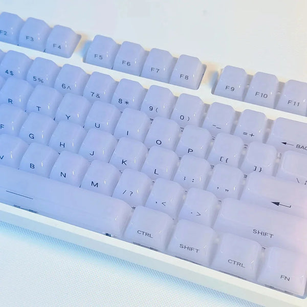 A close-up view of white custom profile keycaps for a mechanical keyboard, showing various letter and function keys.