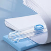 A portable manual paper cutter trimmer with a clear plastic blade is shown resting on a light blue base.