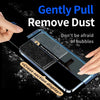Hand gently pulling a dust remover tool across the screen of a smartphone to remove dust and bubbles.