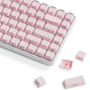 A close-up view of pink translucent ice crystal mechanical keycaps arranged on a white keyboard, with spare keycaps visible.