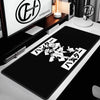 Black extra large gaming mouse pad with white Japanese text design placed on a desk.