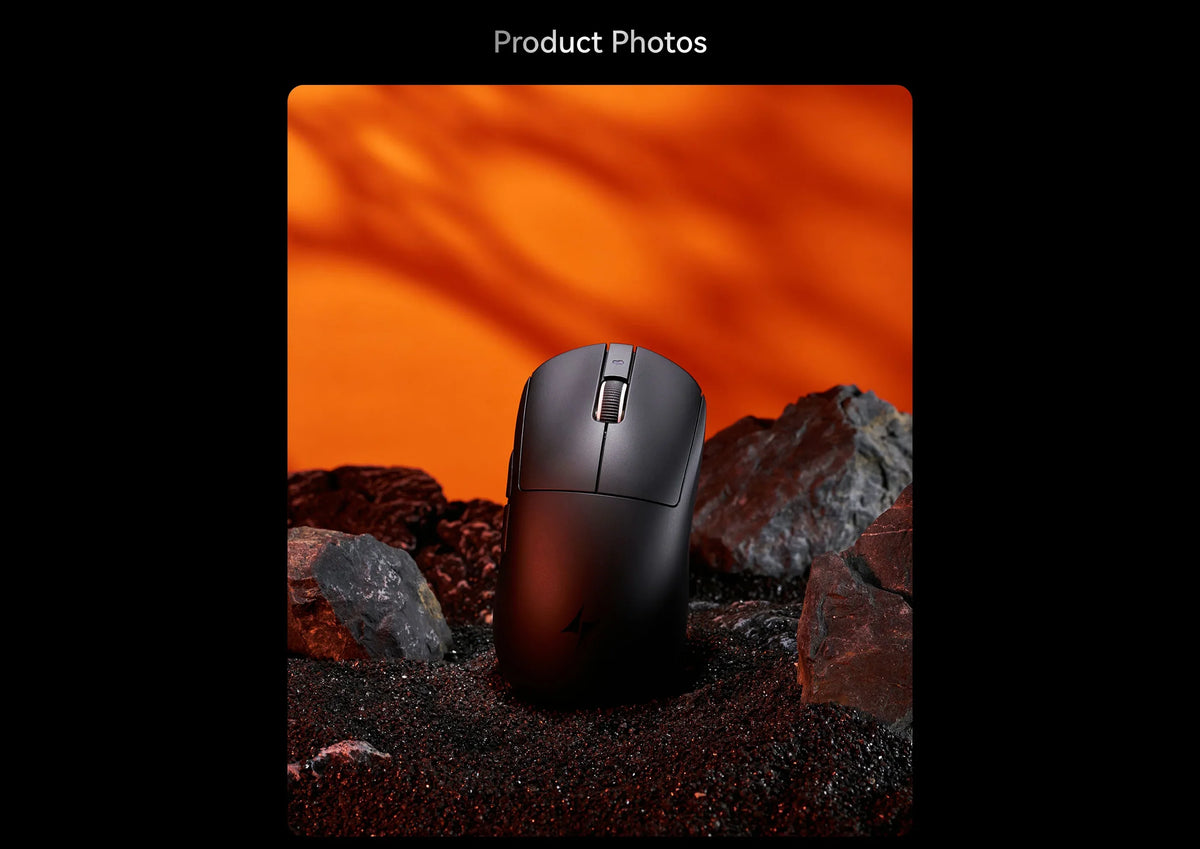 Schwarze ergonomische kabellose Gaming-Maus auf dunklen Felsen mit starken orangefarbenen Schatten.