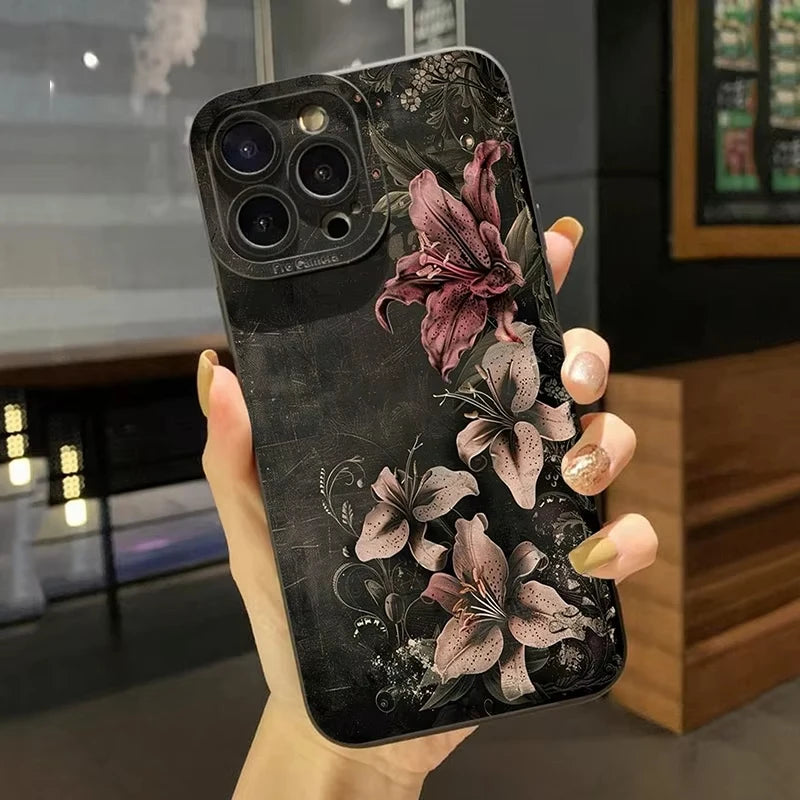A hand holds a black phone case featuring gothic floral art with a large pinkish-purple flower design.