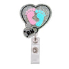 A heart-shaped badge reel holder featuring pink and blue footprints on a sparkly silver background.