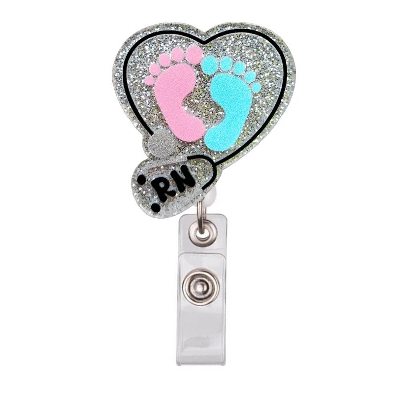A heart-shaped badge reel holder featuring pink and blue footprints on a sparkly silver background.
