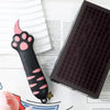 A black cat paw-shaped box cutter with a titanium steel blade resting on a white background.