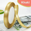 Roll of gold edge satin ribbon with a white center visible on a surface.